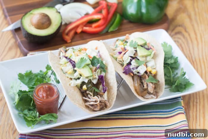 Kickstart Your Year with 28 Wholesome Recipes 3 Flavorful Slow Cooker Pork Tacos served with fresh toppings.