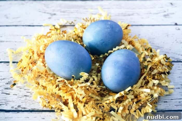 How to Dye Eggs with Blueberries A bowl of natural blueberry egg dye with a white egg submerged, illustrating the dyeing process.