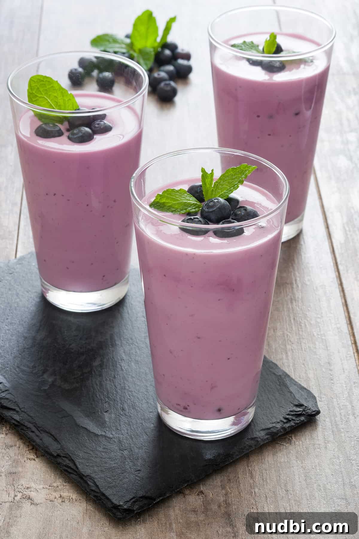 DIY Smoothie Bar Printable and Recipe Kit 3 A vibrant banana, blueberry, and mango smoothie in a glass jar with a straw.