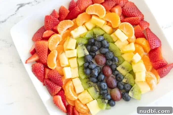 An assortment of colorful fruits arranged in a rainbow pattern on a platter