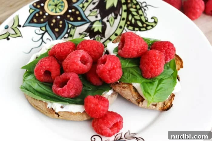 Effortless English Muffin Breakfast Solutions 2 Fresh raspberry and basil on a cream cheese-topped English muffin, highlighting a delightful, no-cook breakfast idea.