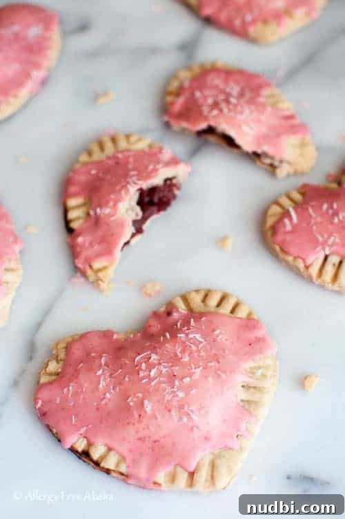 Heart-shaped gluten-free and vegan strawberry pop tarts, frosted with a pink glaze.