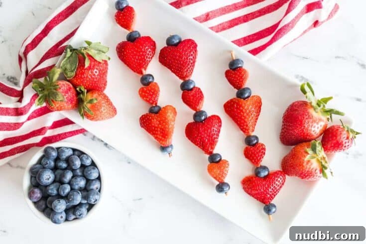 Heart-shaped strawberries on skewers with other berries, perfect for a healthy Valentine's treat.
