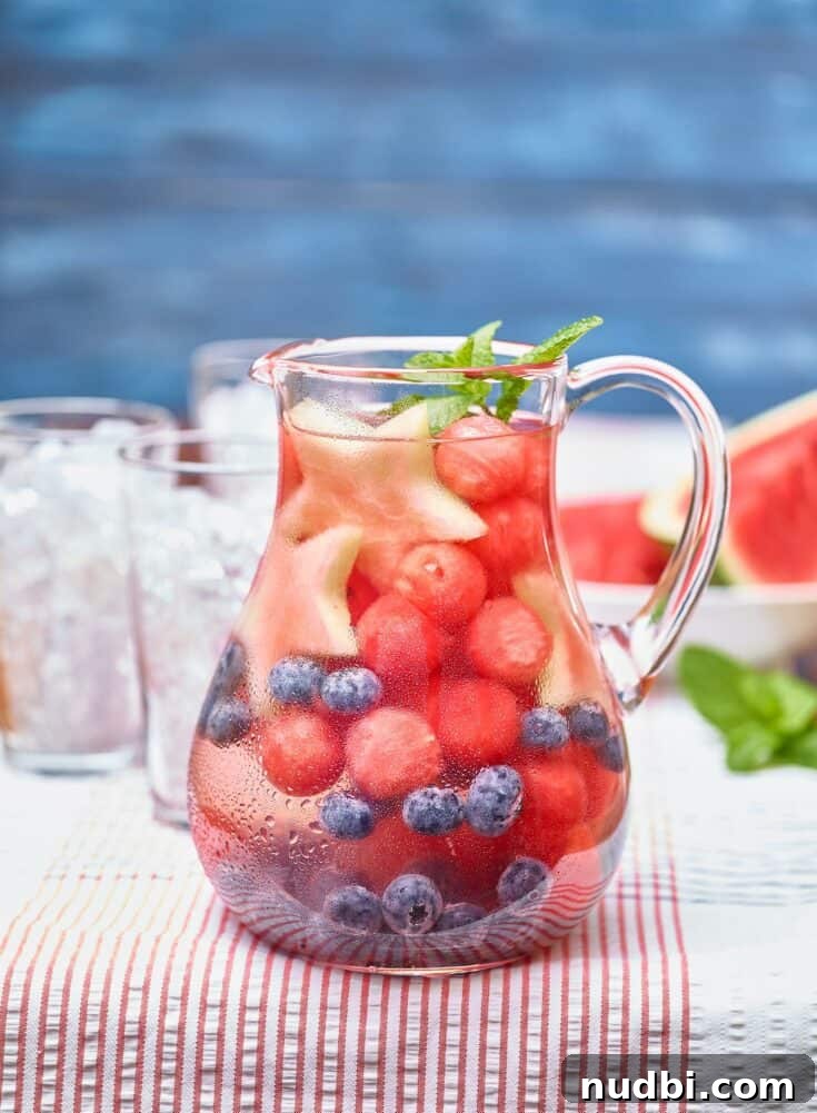 Glass pitcher of watermelon infused water with fresh mint and lime slices.