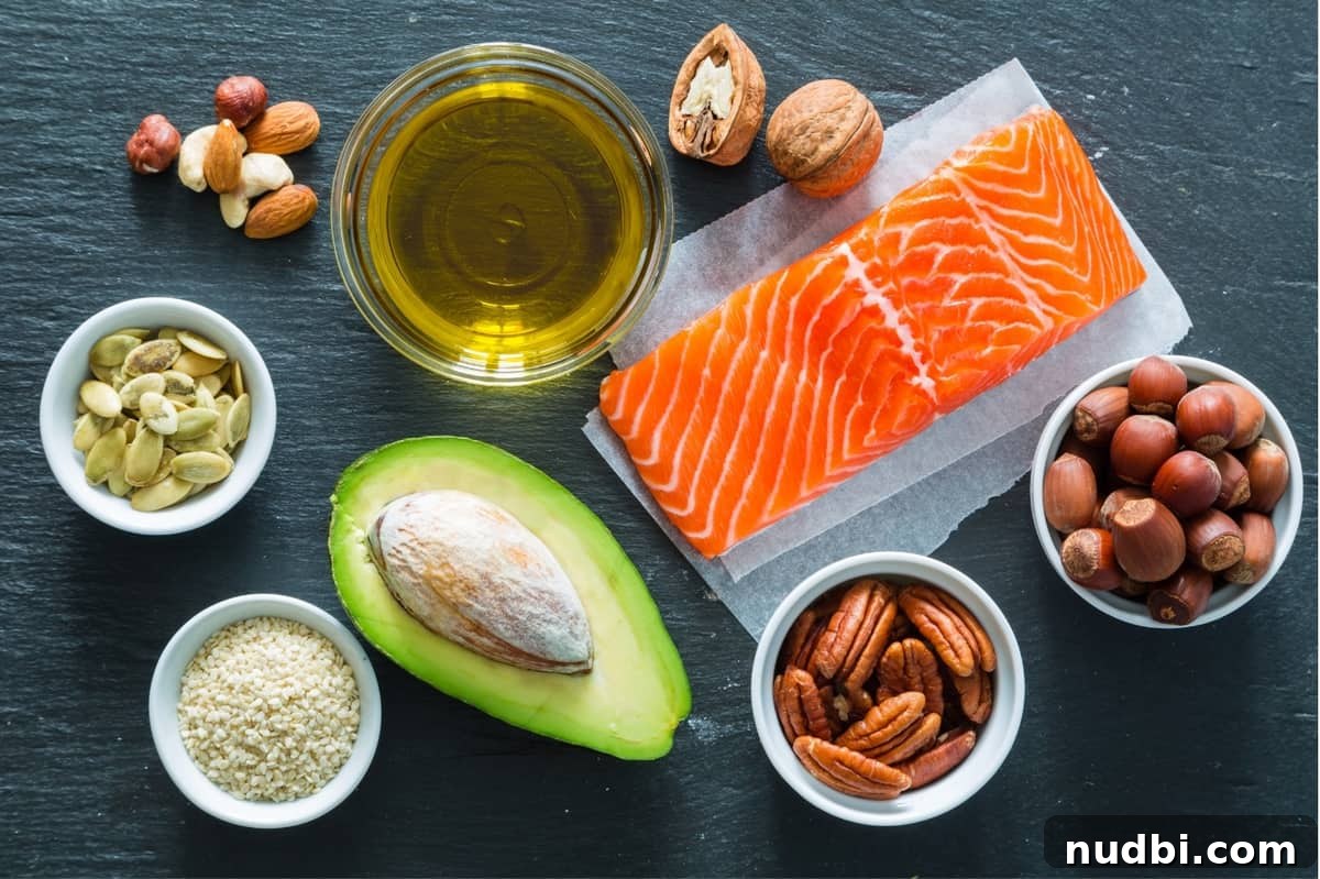 A selection of healthy fats including salmon, avocado, olive oil, and various nuts on a dark background.