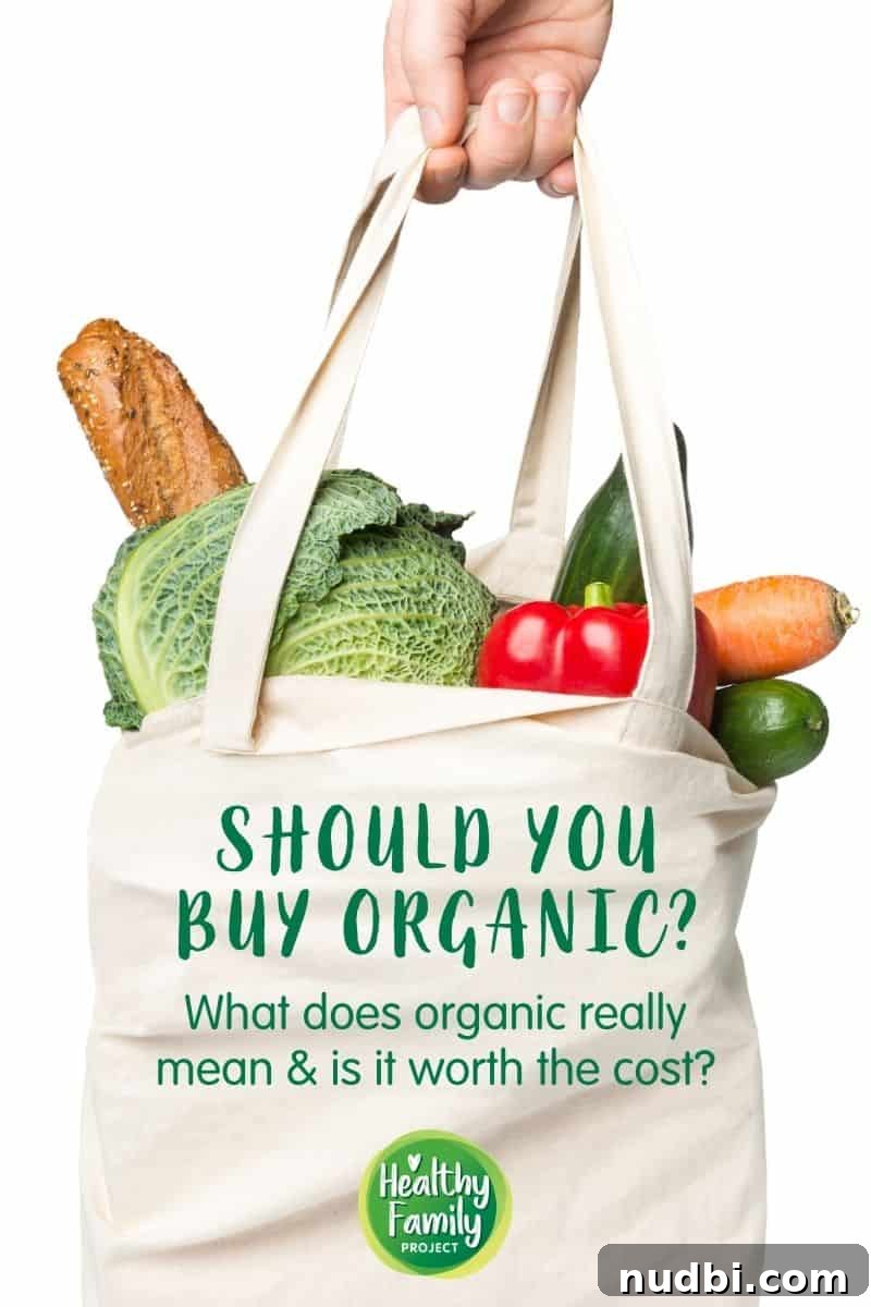 Hand holding a white shopping bag filled with an assortment of fresh, vibrant produce, symbolizing healthy food choices. Text overlay asks: Should You Buy Organic? Get the Facts from a Dietitian.