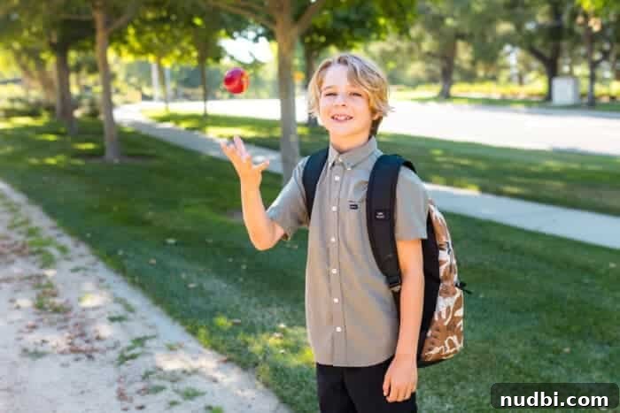 A kid with his backpack ready for school and tossing into the air an apple.