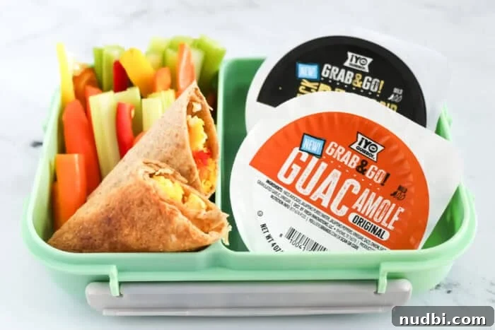 Lunchbox with veggie egg wrap, colorful bell pepper and celery sticks, and two ¡Yo Quiero! Grab & Go dips—guacamole and bean dip, promoting healthy school lunches.