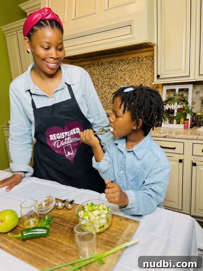 A registered dietitian and her daughter happily cooking together, promoting family wellness and healthy eating habits.