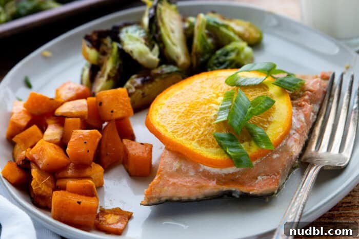 Salmon with roasted vegetables, garnished with green onions.