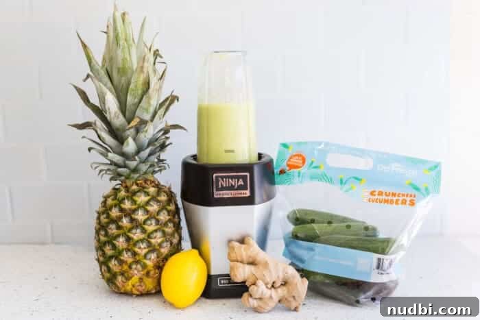 Glass of pineapple cucumber green juice next to fresh ingredients