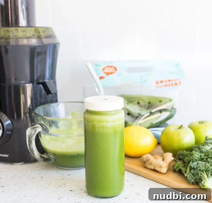 Green juice in a glass with chopped ingredients like kale, apple, and celery