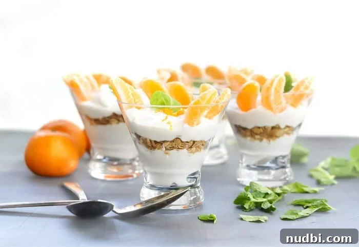 Layered Yogurt Parfait with granola and fresh mandarins in a clear cup