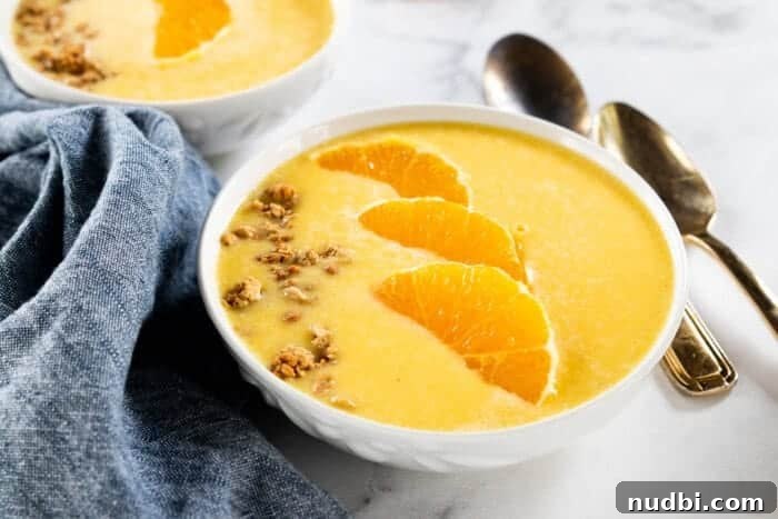 Vibrant Orange Smoothie Bowl topped with fresh fruit, granola, and seeds