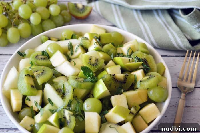 Eat Well This Easter: A Dietitian's Guide to Delicious Balance 4 Close up of vibrant green fruit salad in a white bowl, featuring honeydew, kiwi, and grapes.