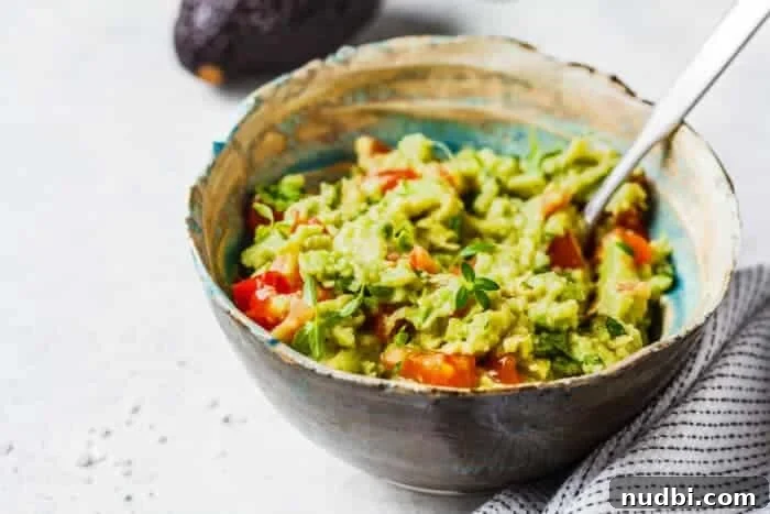 Freshly made guacamole with vibrant green avocados, red onions, cilantro, and lime, ready for dipping.