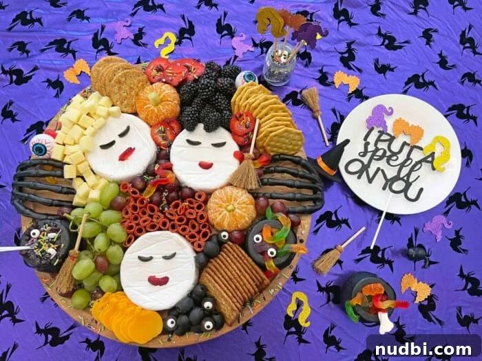 Hocus Pocus themed charcuterie board with brie faces, chorizo, cheese cubes, berries, and candy eyeballs.