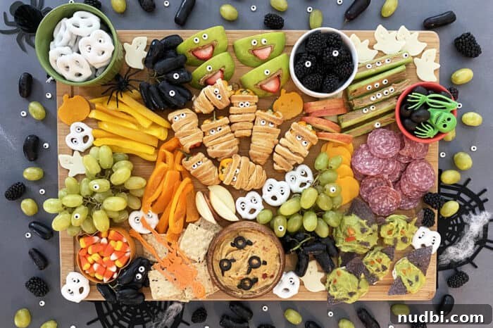 Detailed Halloween snack board filled with fruit, cheese, and various spooky healthy treats.