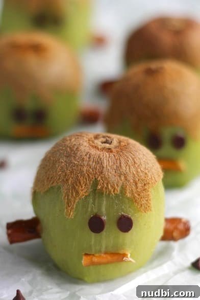 Frankenstein kiwi slices decorated with mini chocolate chips for eyes and mouths.