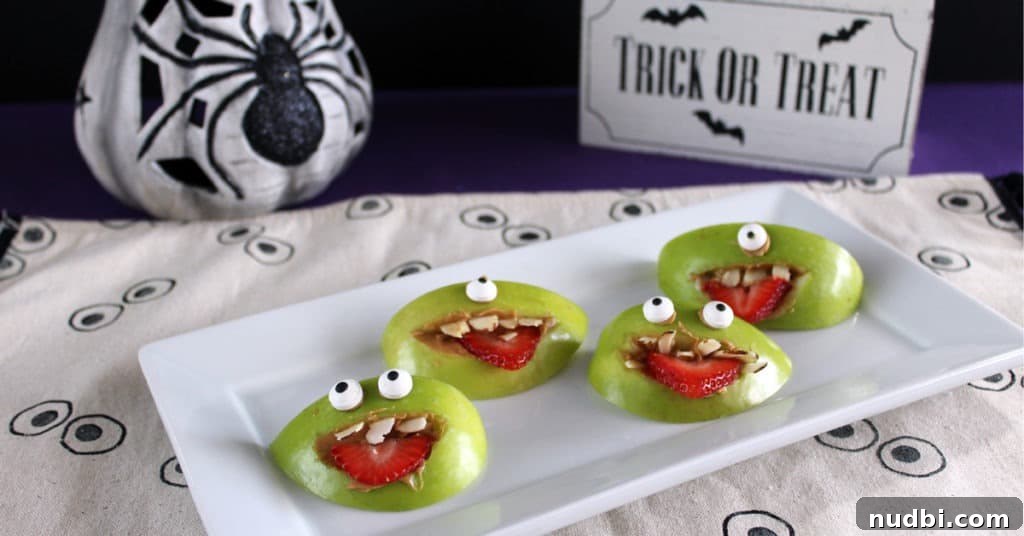 Apple wedges spread with peanut butter, topped with almond fangs, strawberry tongues, and candy eyes to look like spooky monsters.