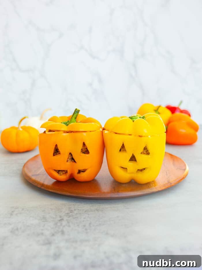 Jack O'Lantern peppers stuffed with meat and cheese, served on a platter.