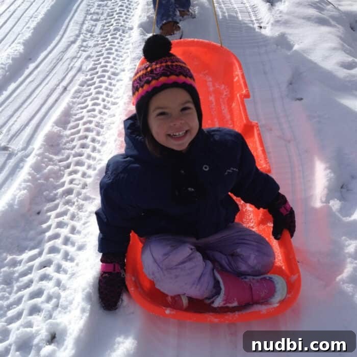Little girl on a winter slide doing outdoor activities to fight winter blues.