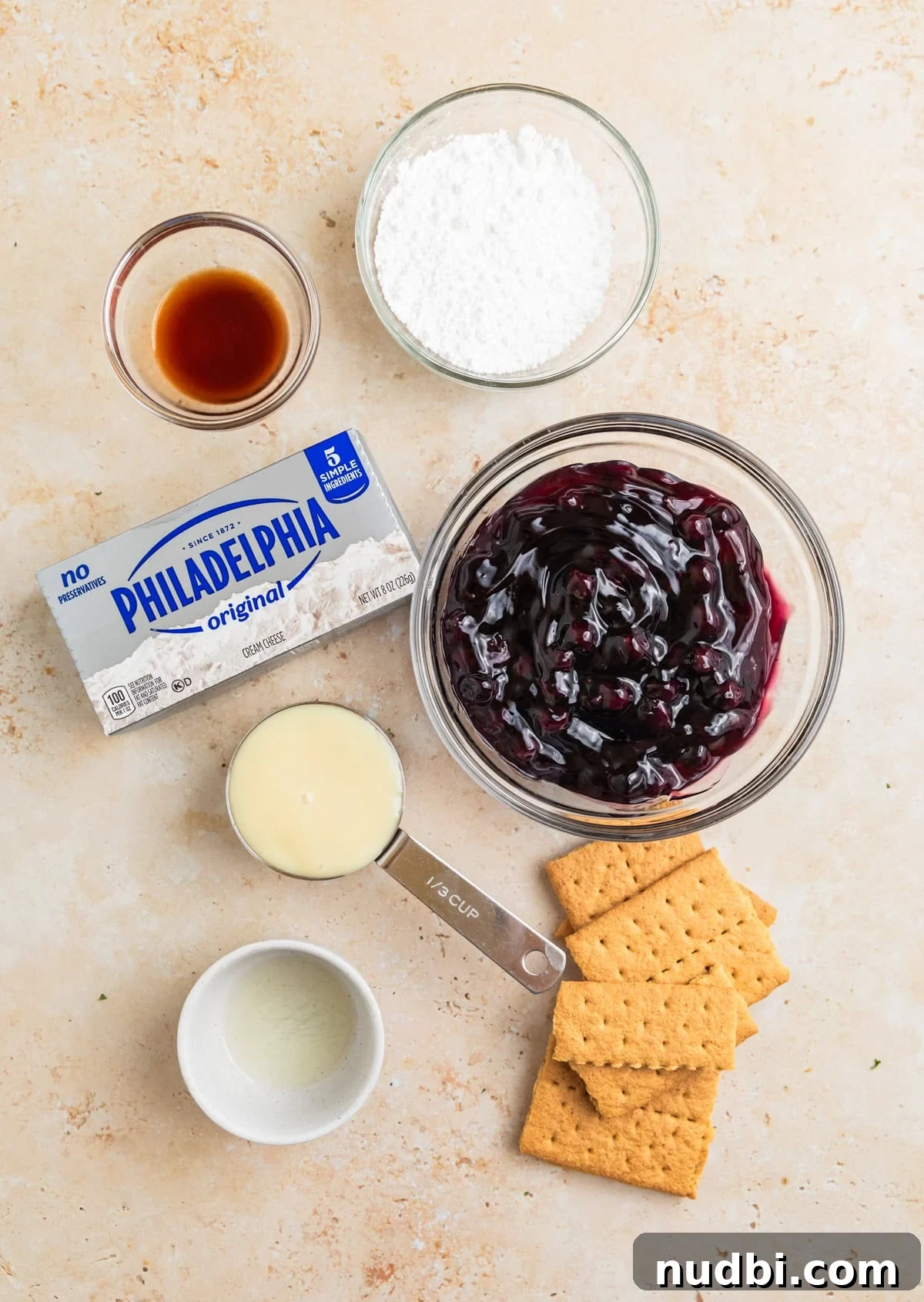 Creamy Blueberry Cheesecake Dip Recipe for Fruit & Crackers 3 Cream cheese, blueberry pie filling and other ingredients arranged on surface.