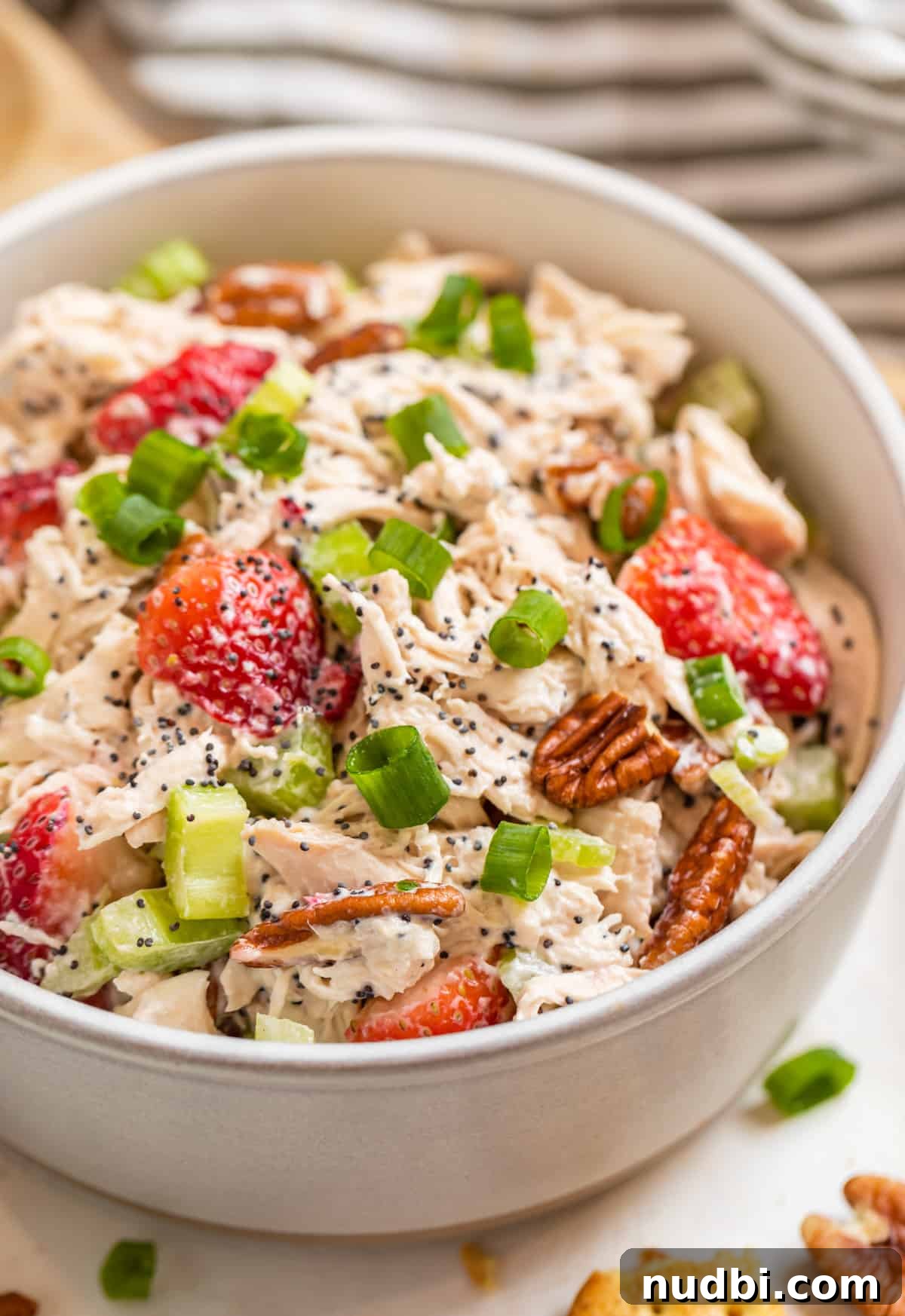 Strawberry Poppy Seed Chicken Salad with Pecans 2 Strawberry chicken salad with pecans, poppy seeds and green onion in ceramic bowl.