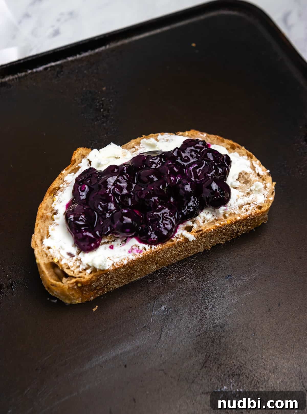 Blueberry, Basil & Goat Cheese Grilled Sandwich Recipe 5 Goat cheese and blueberry sauce on bread on skillet.