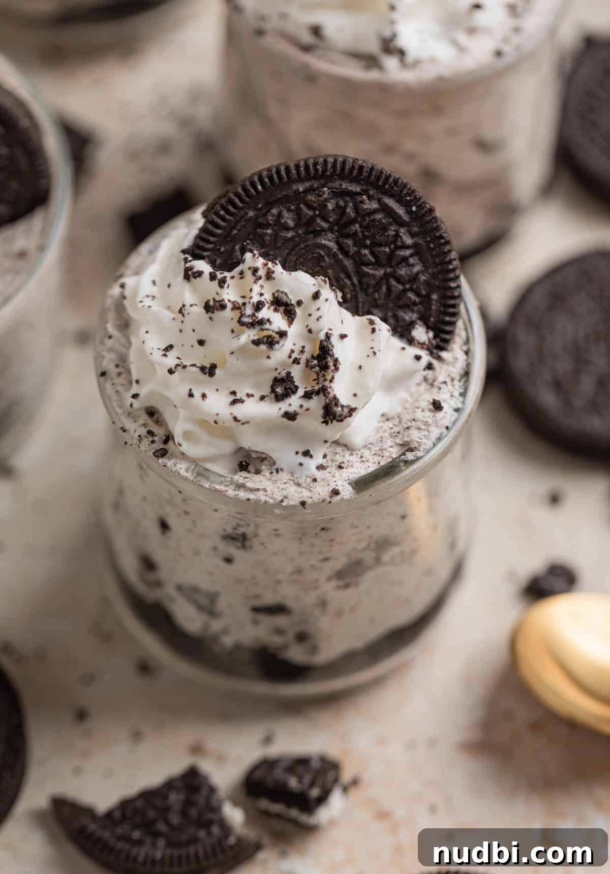 No-Bake Oreo Cheesecake Cups Recipe for Creamy Dessert 2 No bake Oreo cheesecake cup topped with whipped cream and crushed Oreo cookies.