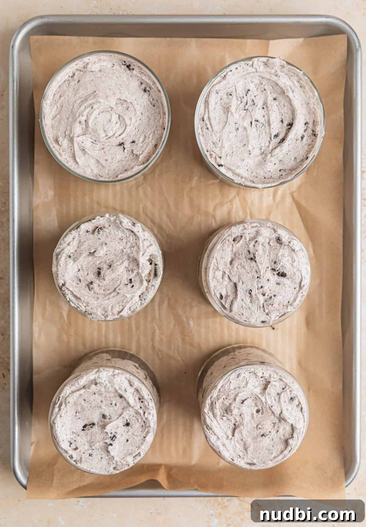 No-Bake Oreo Cheesecake Cups Recipe for Creamy Dessert 12 Glass dishes filled with no bake Oreo cheesecake.