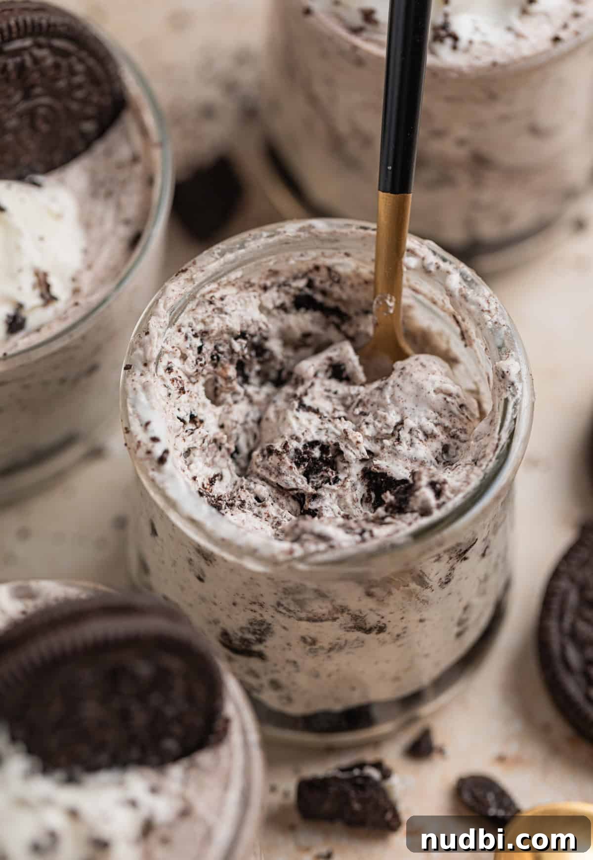 No-Bake Oreo Cheesecake Cups Recipe for Creamy Dessert 13 Spoon in glass dessert glass with Oreo cheesecake mixture.
