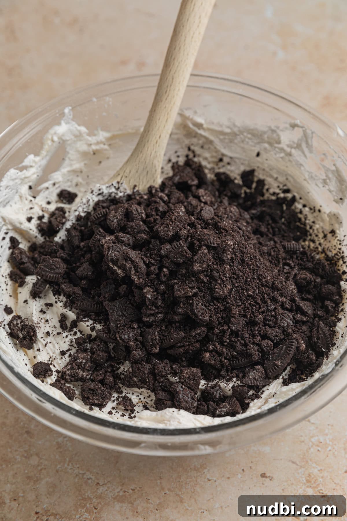 No-Bake Oreo Cheesecake Cups Recipe for Creamy Dessert 10 Crushed Oreos added to no bake Oreo cheesecake mixture in bowl.