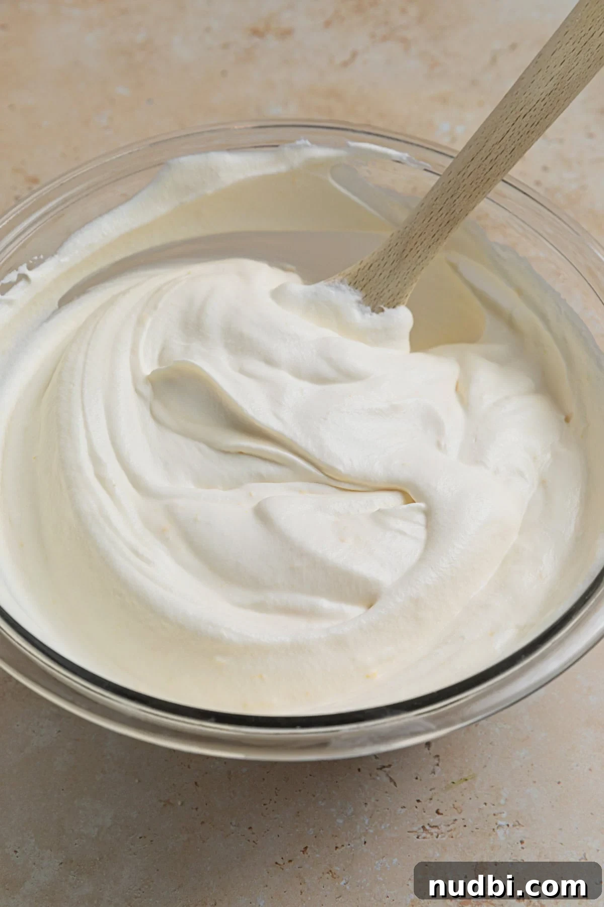No-Churn Lemon Ice Cream Recipe — Creamy, Tart & Refreshing 7 No churn lemon ice cream mixture in bowl with wooden spoon.