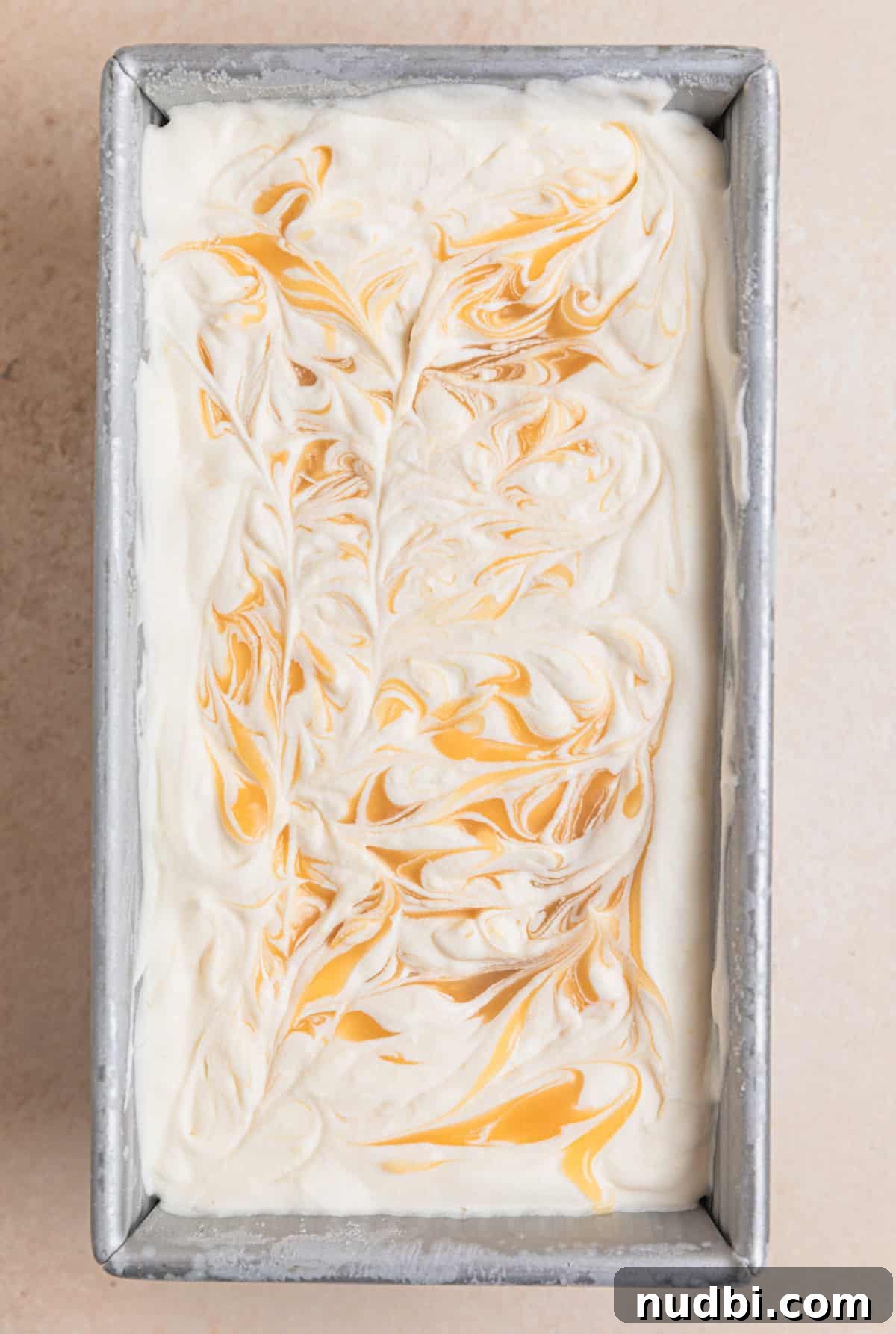 No-Churn Lemon Ice Cream Recipe — Creamy, Tart & Refreshing 10 Frozen homemade lemon ice cream in container with lemon curd swirls.