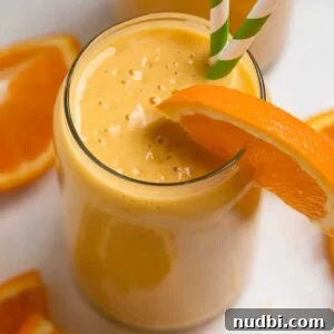 Orange Creamsicle Protein Smoothie Recipe for Creamy Vitamin C Boost 5 Orange banana smoothie in glass with orange slice to garnish and green striped straws.