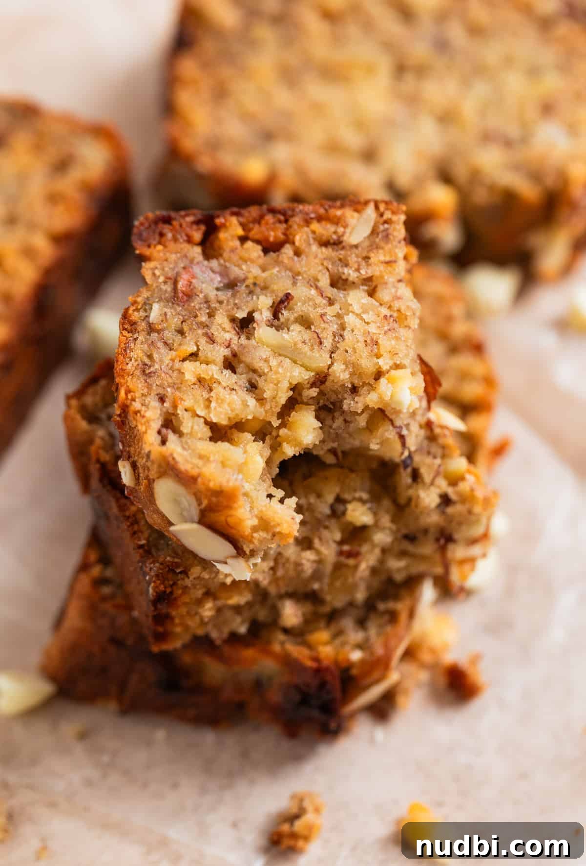 White Chocolate and Almond Banana Bread Recipe 3 Slices of banana bread stacked and bite taken out of top piece.