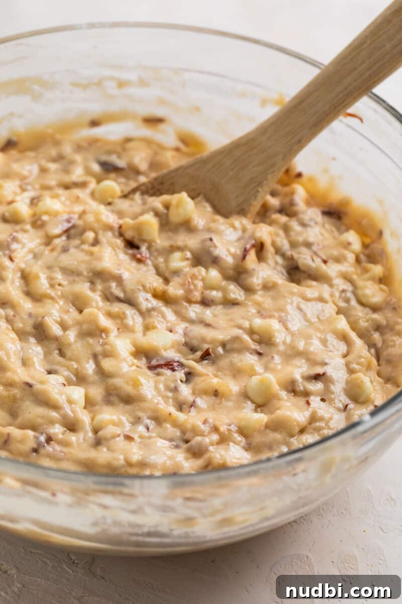 White Chocolate and Almond Banana Bread Recipe 4 Banana bread mixture in glass mixing bowl with wooden spoon.