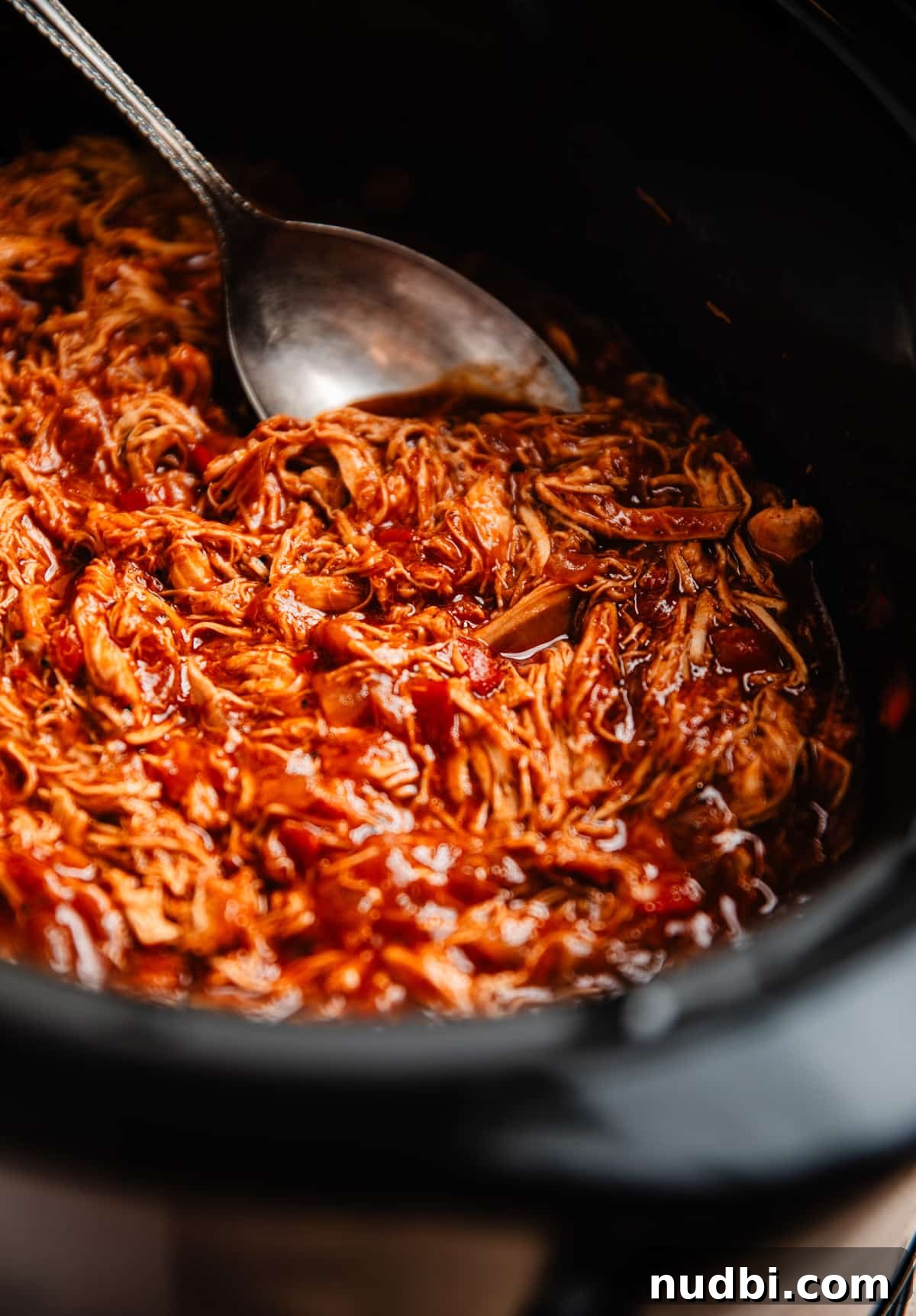 Slow Cooker BBQ Shredded Chicken Recipe for Sandwiches and Tacos 3 Crock pot with shredded BBQ chicken prepared and serving spoon scooping into it.