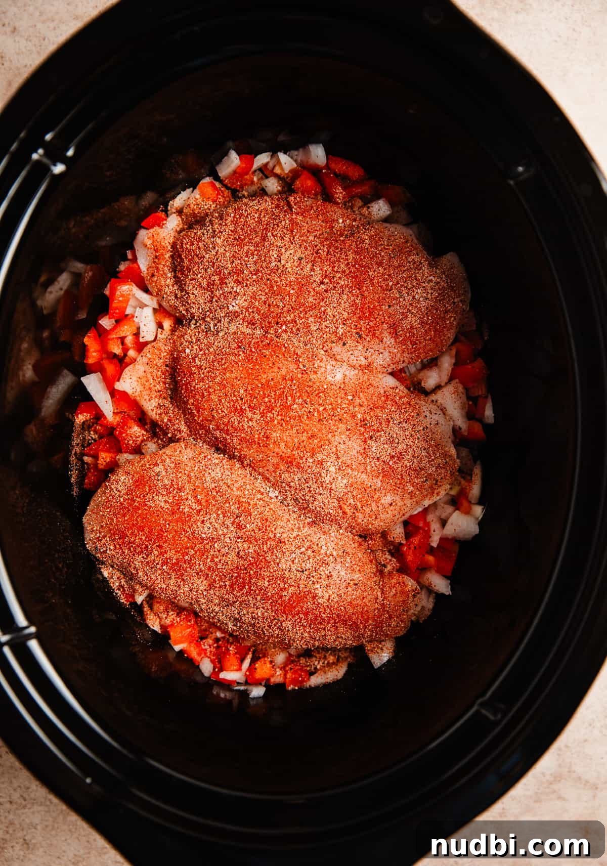 Slow Cooker BBQ Shredded Chicken Recipe for Sandwiches and Tacos 4 Chicken breasts with spice rub on onions and peppers in crockpot.