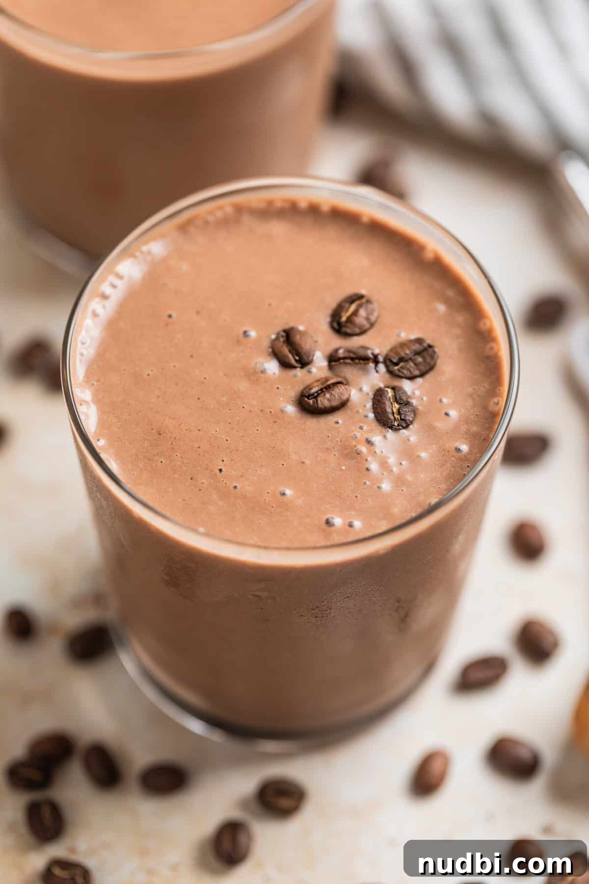Peanut Butter Coffee Smoothie Recipe — Creamy Protein Boost 2 Peanut butter coffee smoothie in glass topped with coffee beans.