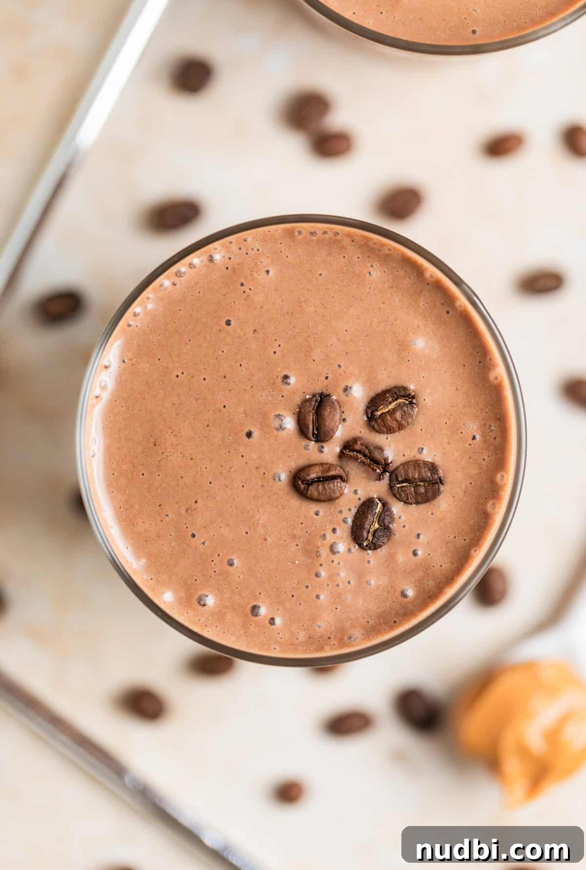 Peanut Butter Coffee Smoothie Recipe — Creamy Protein Boost 6 Peanut Butter coffee smoothie with peanut butter on spoon and coffee beans beside the glass.