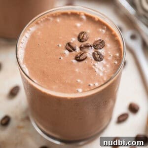 Peanut Butter Coffee Smoothie Recipe — Creamy Protein Boost 7 Peanut butter coffee smoothie in glass with coffee beans on top.