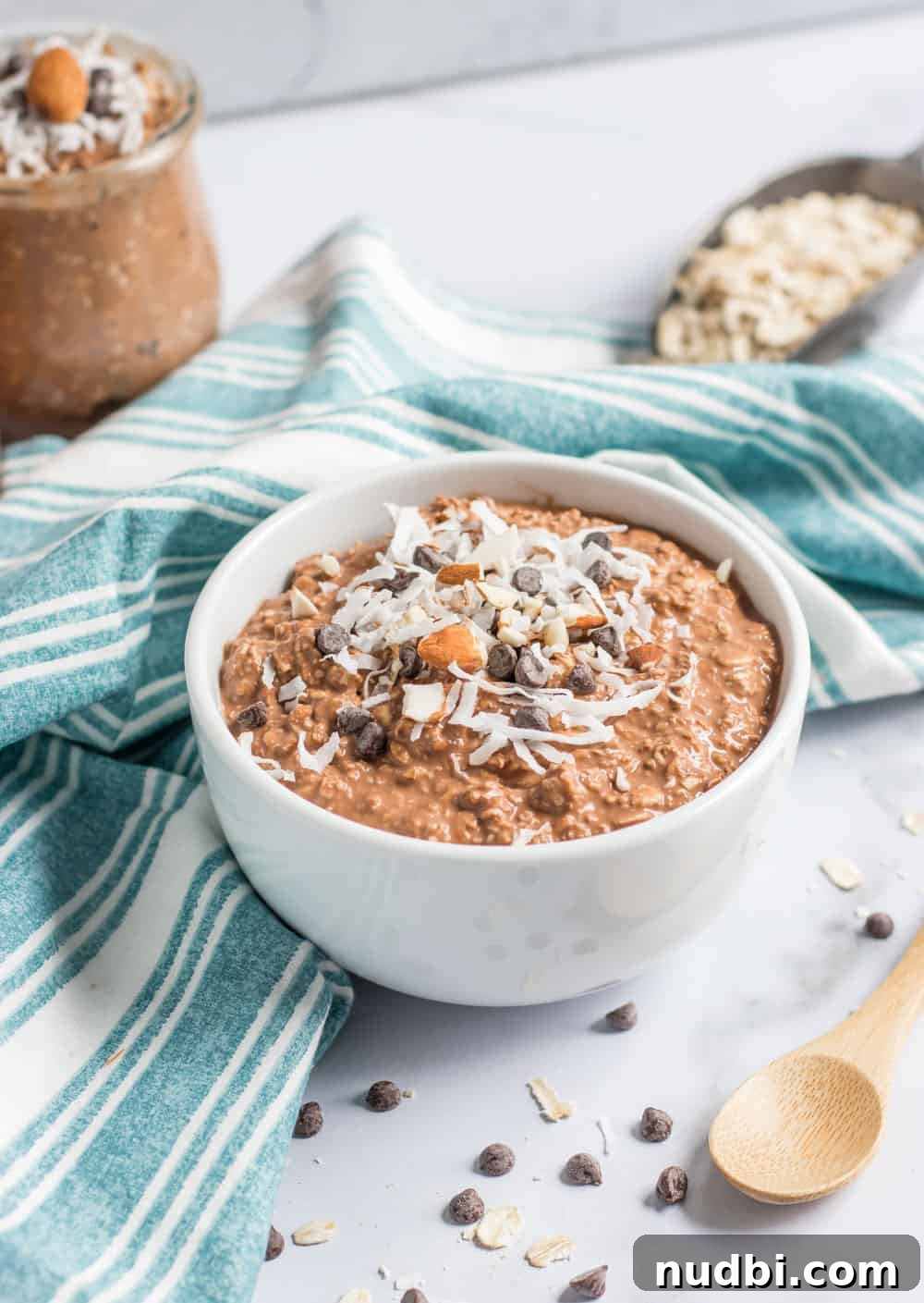 Almond Joy Overnight Oats Recipe — Chocolate, Coconut & Almonds 3 Chocolate overnight oats in white bowl with chocolate chips and coconut.