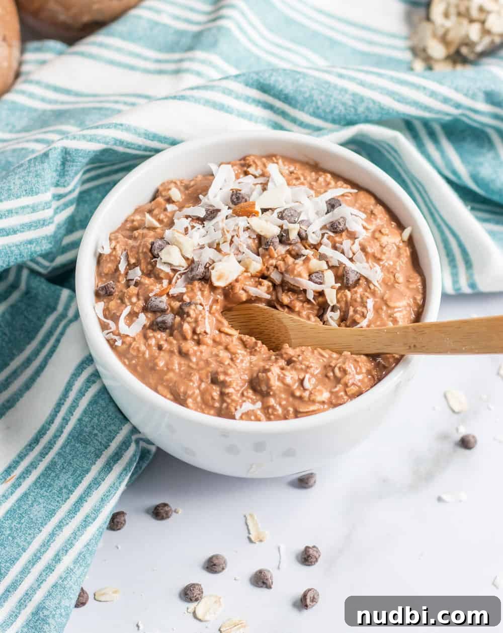 Almond Joy Overnight Oats Recipe — Chocolate, Coconut & Almonds 5 Spoon in bowl of almond joy overnight oatmeal with chocolate chips.