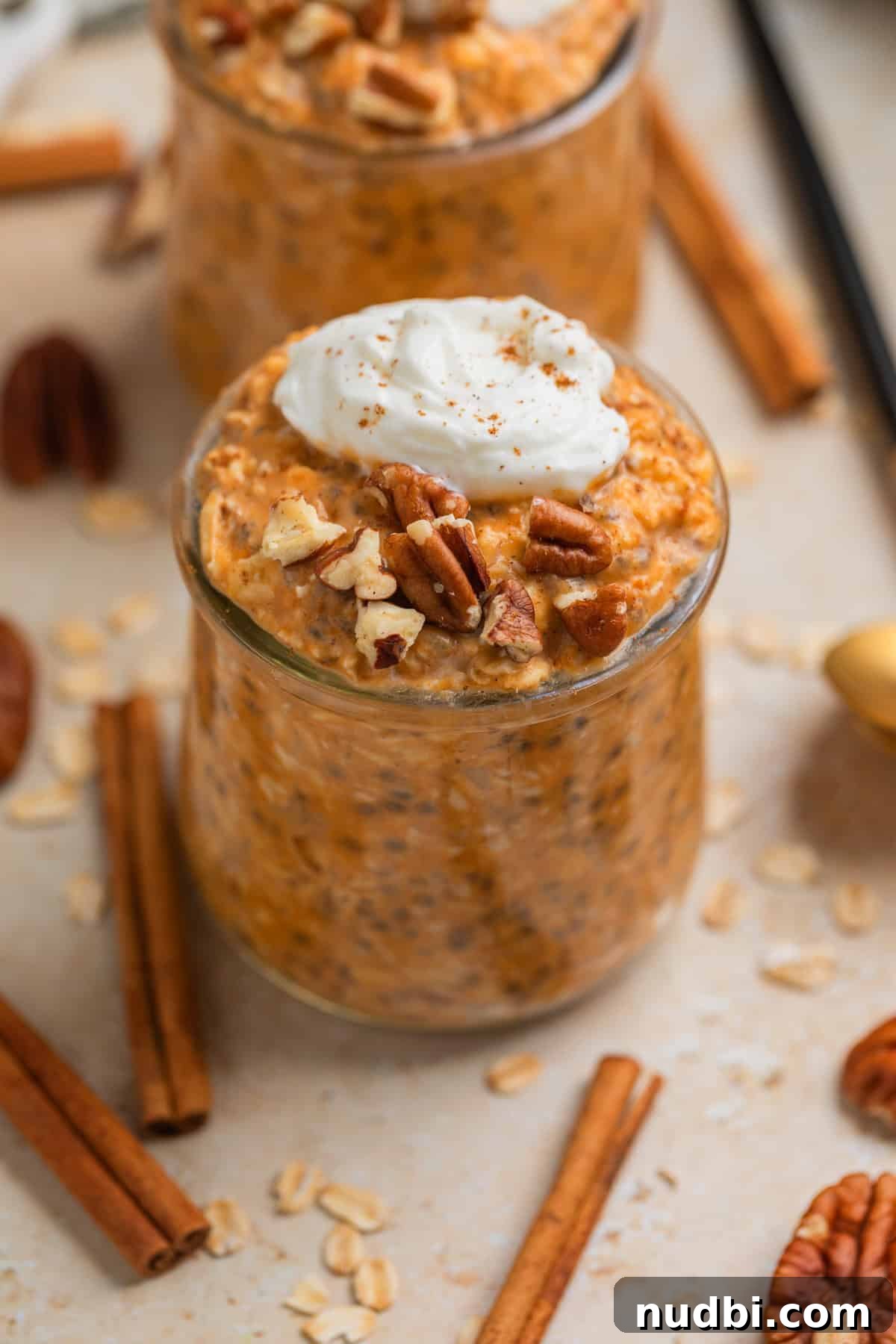 Pumpkin Pie Overnight Oats Recipe for Cozy Fall Breakfast 2 Glass jar with pumpkin pie overnight oats topped with whipped cream and chopped pecans.