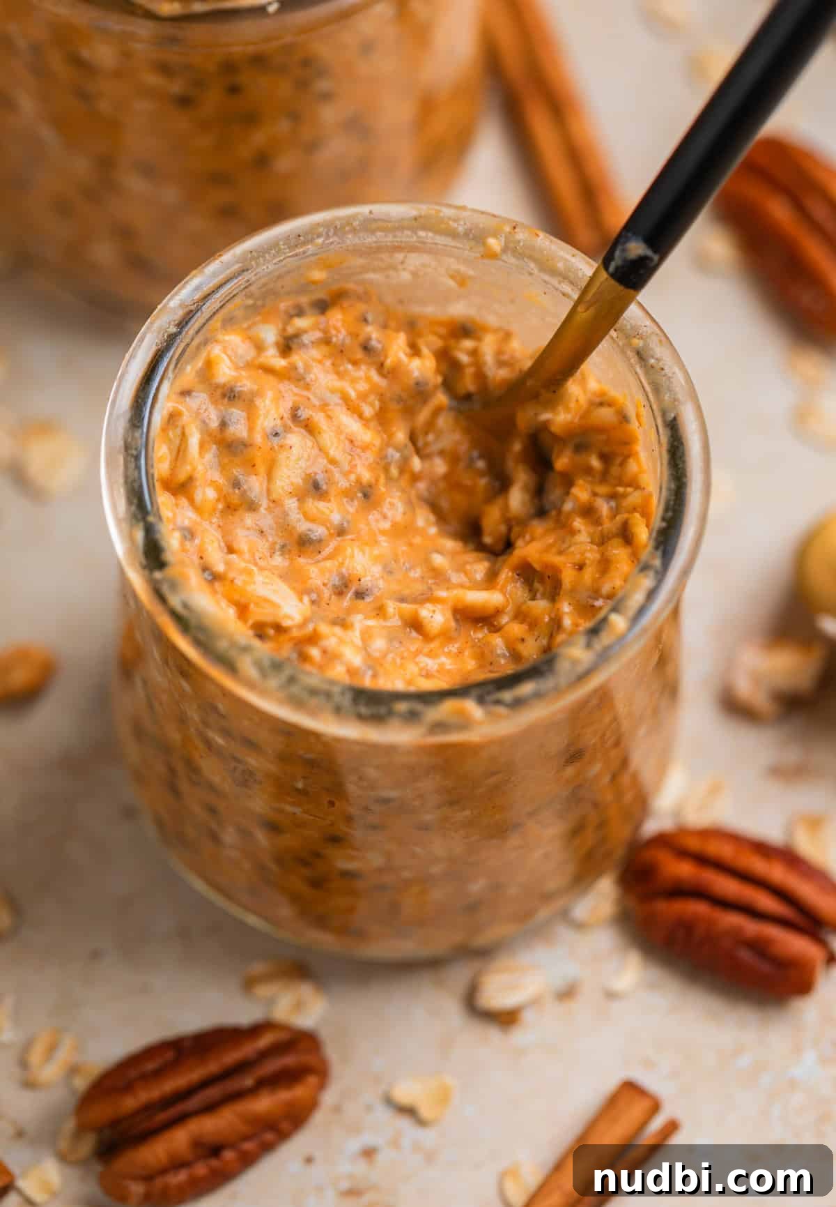 Pumpkin Pie Overnight Oats Recipe for Cozy Fall Breakfast 4 Jar with spoon scooping into pumpkin oatmeal.