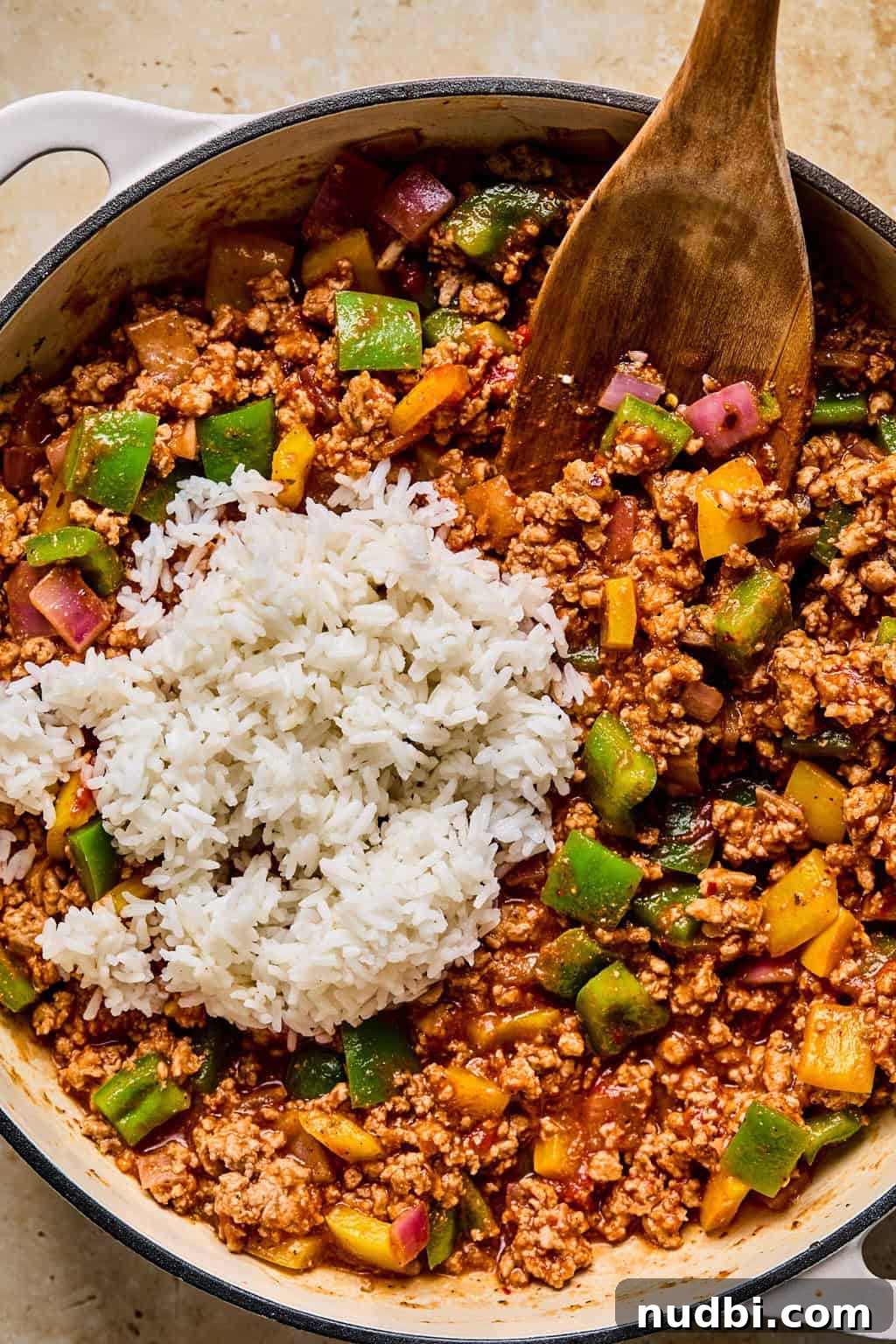 Weeknight Ground Turkey Skillet Dinner Recipe 8 Cooked rice added to simple ground turkey skillet with wooden spoon in pan.