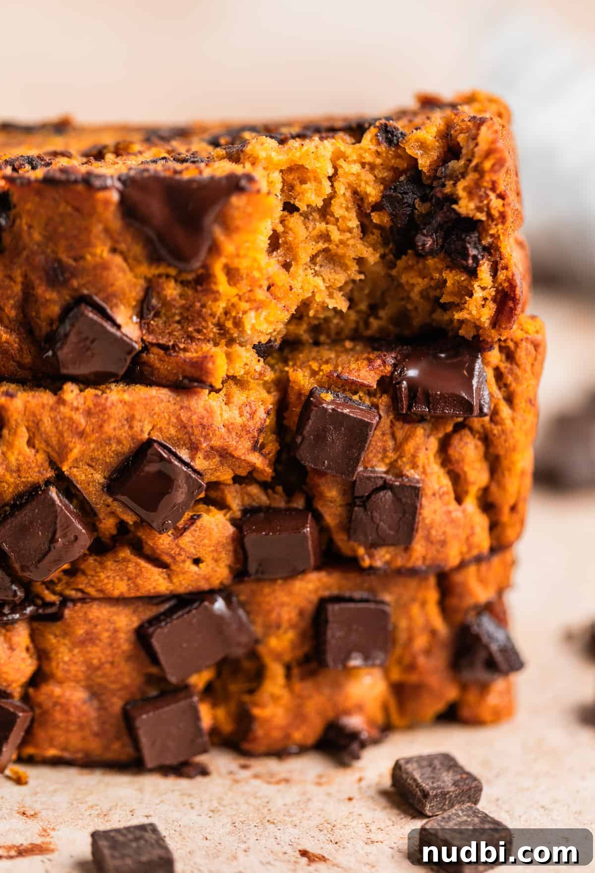 Pumpkin Chocolate Chip Banana Bread Recipe 2 Sliced pumpkin chocolate chip banana bread on counter with dark chocolate chunks surrounding.