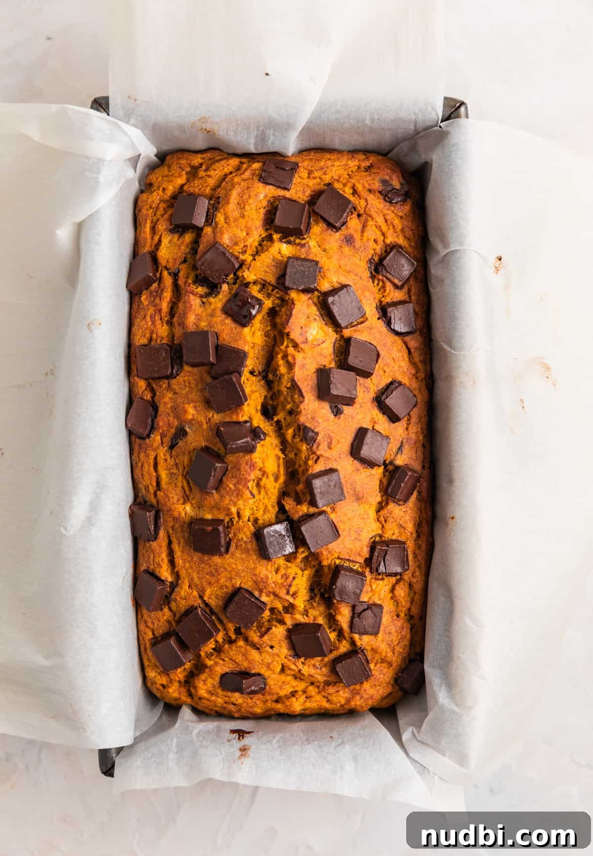Pumpkin Chocolate Chip Banana Bread Recipe 6 Baked pumpkin chip banana bread in bread pan lined with parchment.